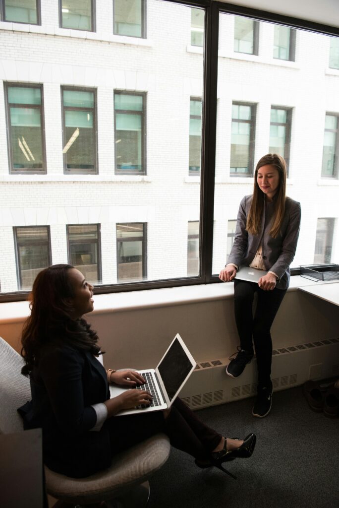 Two Women Talking White Holding Laptop Computers